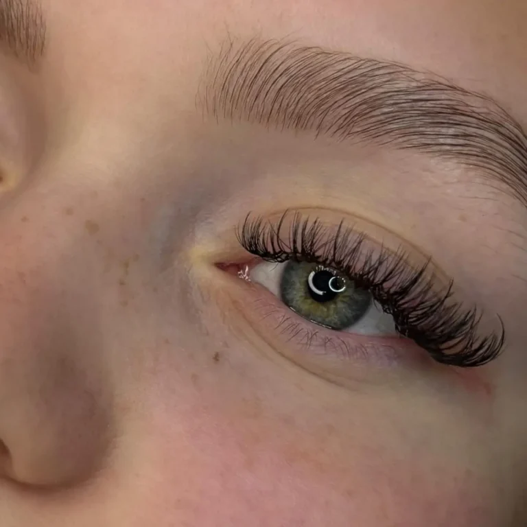 Lähikuva asiakkaan silmästä, jossa on ripsipidennykset ja huolitellut kulmat.